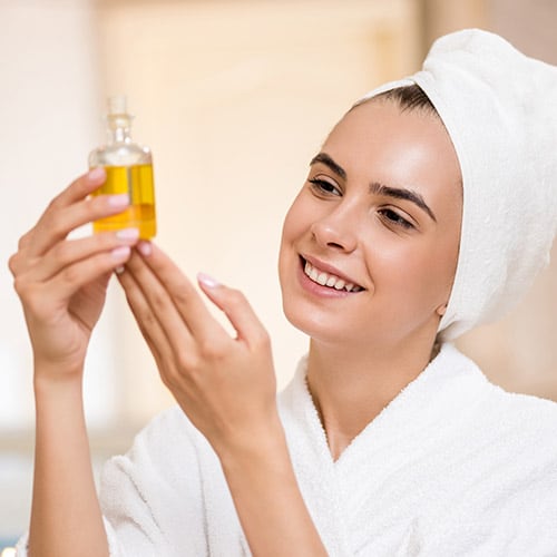 Woman smiling in a robe holding a serum