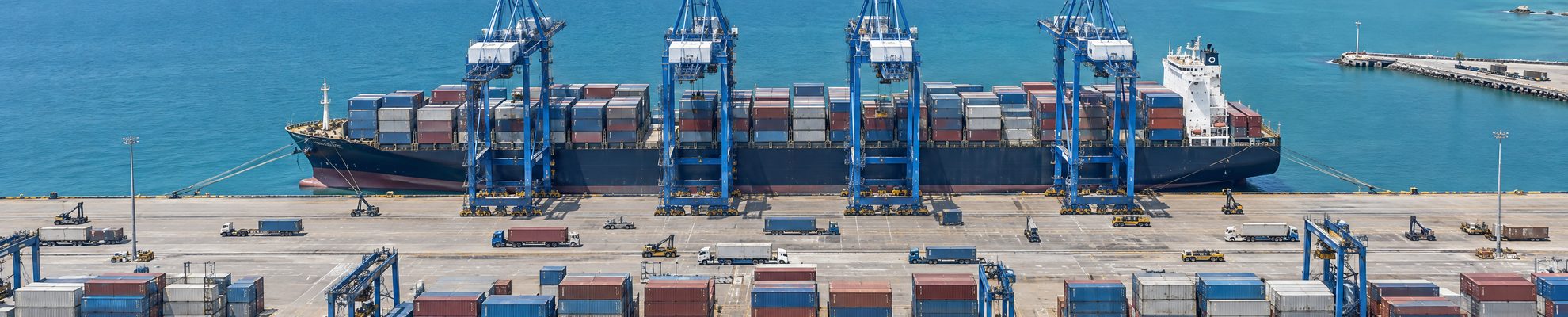Vista aérea de un buque portacontenedores cargando en una terminal portuaria de Costa Rica, la ruta de exportación hacia Estados Unidos y Europa